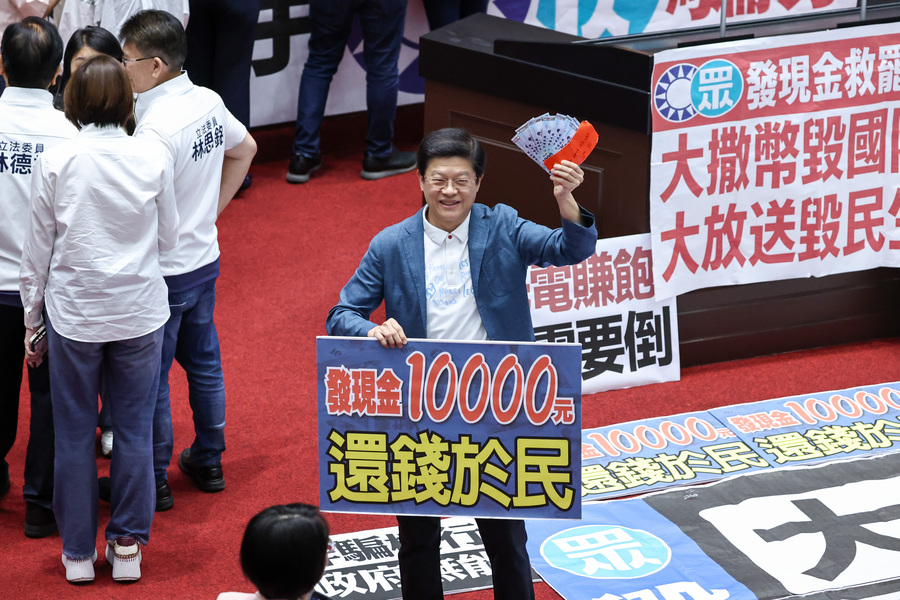 圖為登記發言時,國民黨立委羅明才(中)拿著鈔票與標語留影。(中央社)